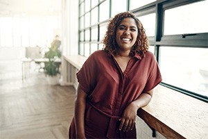 a smiling woman leaning against a table